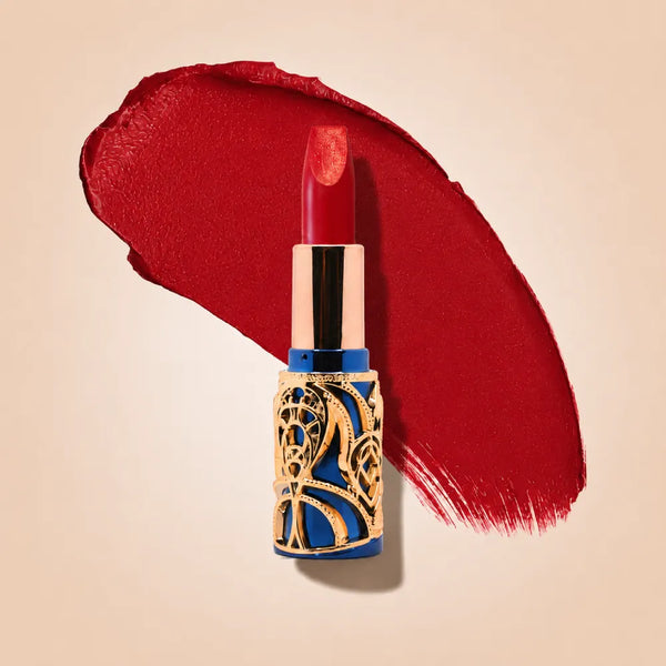 Swiss Miss Bling Lipstick in shade Velvet Sin B-110 featuring ornate blue and gold filigree bullet tube casing with a rich classic red lipstick swatch.