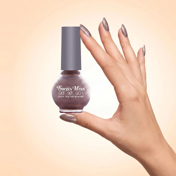 Swiss Miss Get Set Go Quick Dry Nail Enamel in shade Maple Sugar 831 held by hand showing round glass bottle with shimmering metallic dusty taupe brown polish and matching manicured nails.