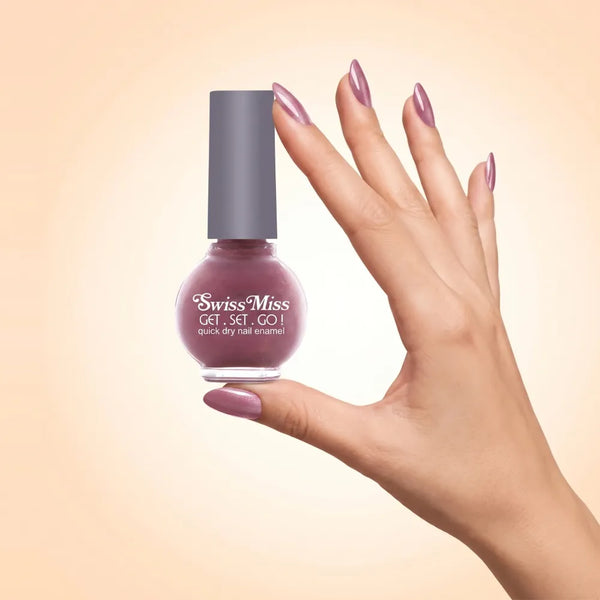 Swiss Miss Get Set Go Quick Dry Nail Enamel in shade Sugar Pink 209 held by hand showing round glass bottle with shimmering dusty mauve pink polish and matching manicured nails.