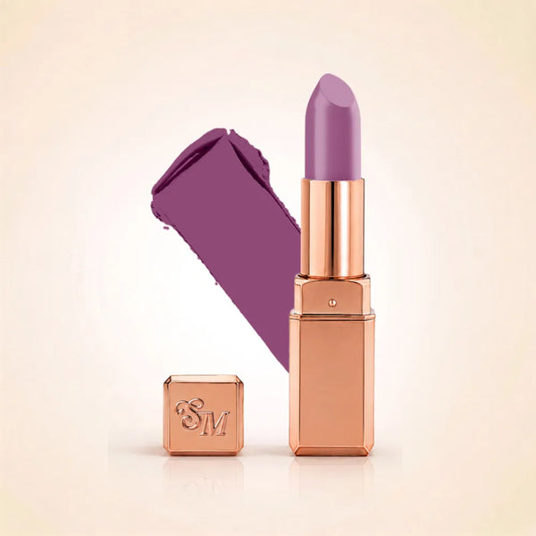 Swiss Miss Silk Lipstick in shade Lilac Mauve (723) in gold bullet packaging shown alongside a textured cream color swatch.