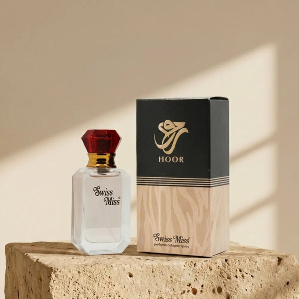 Swiss Miss Hoor Perfume 15ml bottle with red diamond cap beside black and beige packaging box on a stone pedestal