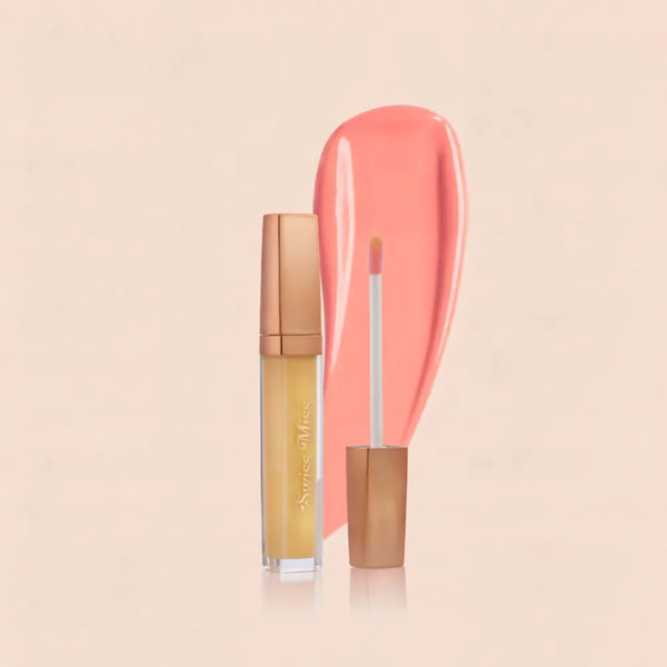 Swiss Miss lip gloss tube with a metallic rose gold cap, applicator wand, and a glossy peach-pink swatch background.