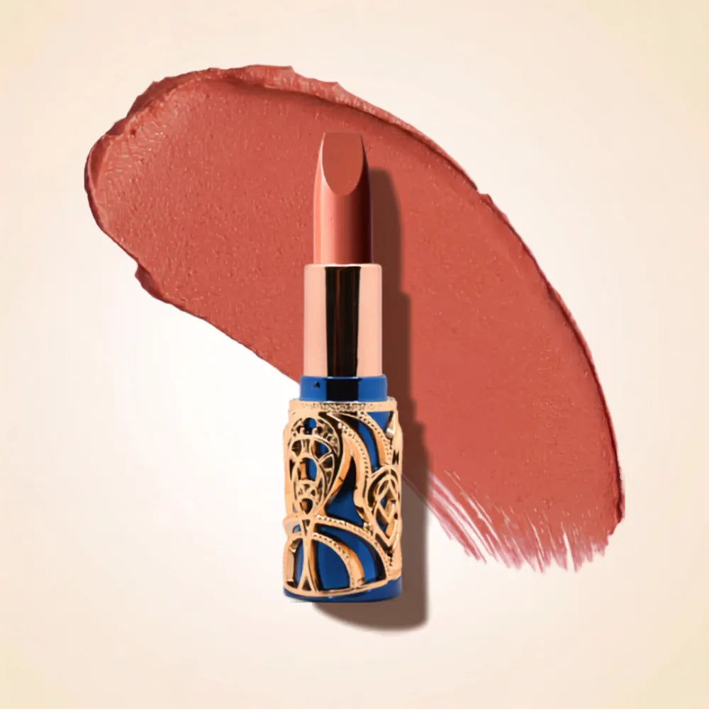 Swiss Miss Bling Lipstick in shade Nude Pink B-103 featuring ornate blue and gold filigree bullet tube casing with a warm peachy nude pink lipstick swatch.