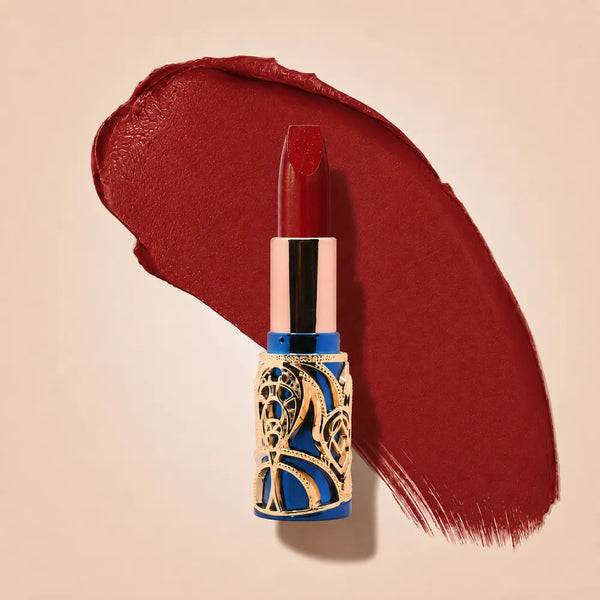 Swiss Miss Bling Lipstick in shade The Signature Muse B-115 featuring ornate blue and gold filigree bullet tube casing with a red lipstick swatch.