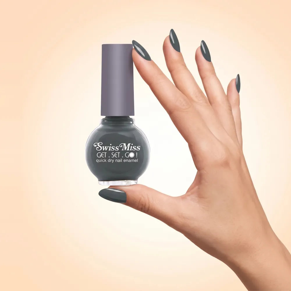 Swiss Miss Get Set Go Quick Dry Nail Enamel in shade Olive Grey F-405 held by hand showing round glass bottle with smooth deep muted olive grey polish and matching manicured nails.