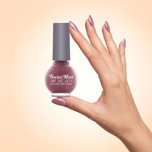 Swiss Miss Get Set Go Quick Dry Nail Enamel in shade Sugar Pink 209 held by hand showing round glass bottle with shimmering dusty mauve pink polish and matching manicured nails.