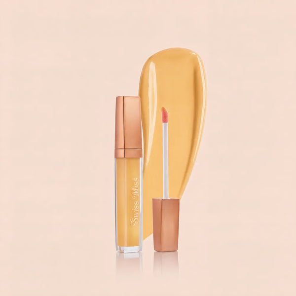 Swiss Miss High Shine Lip Gloss in shade 60 Magic Glow featuring rose gold cap, applicator wand, and warm yellow lip gloss swatch.