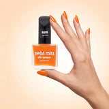 Swiss Miss Silk Lacquer Nail Enamel in shade Apricot 626 held by hand showing clear glass square bottle with bright apricot orange polish and matching manicured nails.