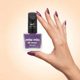Swiss Miss Silk Lacquer Nail Enamel in shade Dewy Rose 617 held by hand showing clear glass square bottle with deep plum mauve purple polish and matching manicured nails.