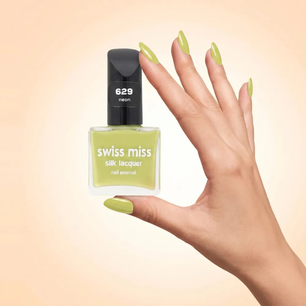 Swiss Miss Silk Lacquer Nail Enamel in shade Neon 629 held by hand showing clear glass square bottle with vibrant neon chartreuse lime green polish and matching manicured nails.
