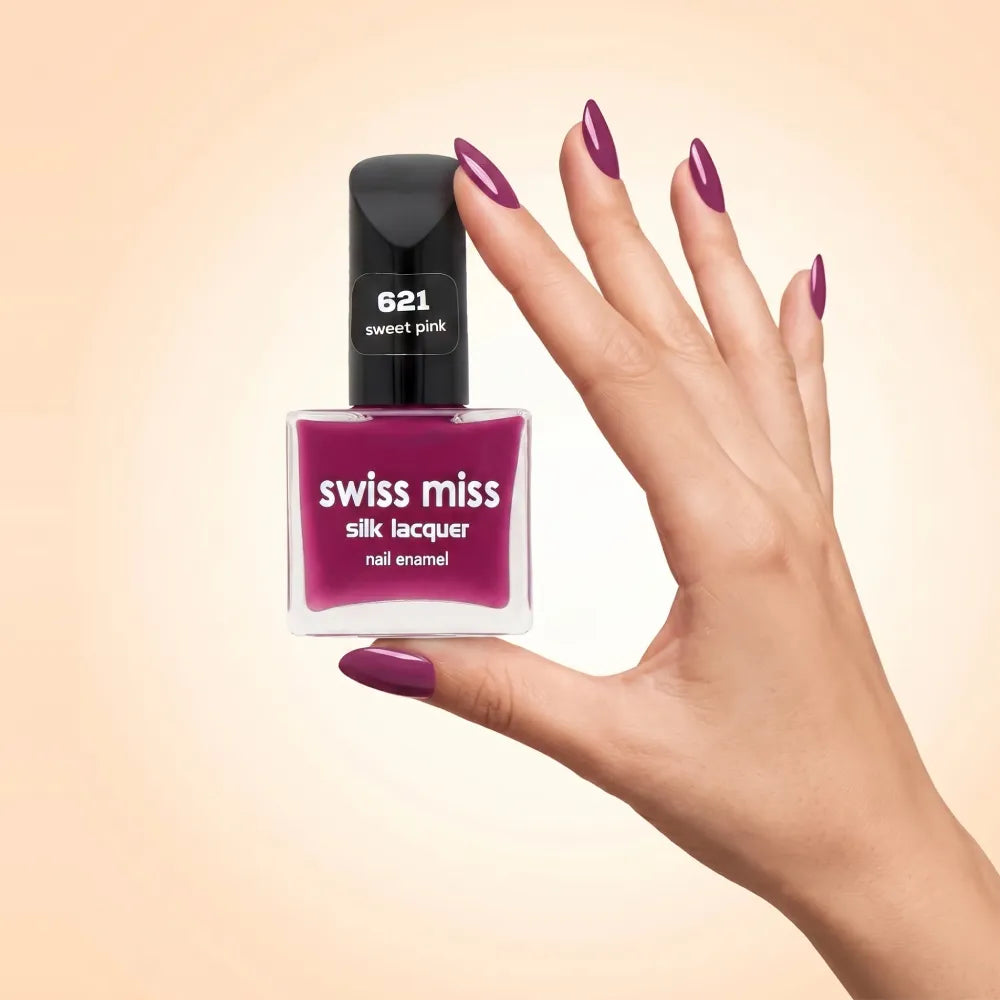 Swiss Miss Silk Lacquer Nail Enamel in shade Sweet Pink 621 held by hand showing clear glass square bottle with deep berry orchid pink polish and matching manicured nails.