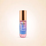 A body mist bottle with pump by Swiss Miss, labeled 'Vanilla Charm', featuring a metallic rose gold cap and a body of liquid with a vertical rainbow gradient of pink, purple, blue, and green, set against a soft beige background.