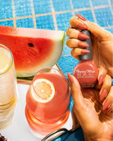 Hand holding Swiss Miss Autumn Blaze F-408 Get Set Go quick dry nail enamel bottle displaying warm burnt terracotta coral polish applied on long nails.