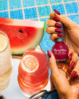 Hand holding Swiss Miss Cherry Charisma F-409 Get Set Go quick dry nail enamel bottle displaying rich deep cherry red shimmer polish applied on long nails.