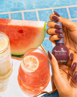 Woman holding Swiss Miss Get Set Go quick dry nail polish bottle in Flint Vista 242 with a muted mauve brown manicure by a pool.