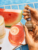 Hand holding Swiss Miss Golden Hour F-404 Get Set Go quick dry nail enamel bottle displaying warm golden tan-brown polish applied on long nails.