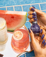 Woman holding Swiss Miss Get Set Go quick dry nail polish bottle in Grape Purple 212 with a matching deep purple shimmery manicure by a pool.