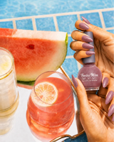 Hand holding Swiss Miss Lilac Sizzle 250 Get Set Go quick dry nail enamel bottle displaying shimmering lilac polish applied on long nails.