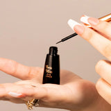 Hand holding an open Swiss Miss black liquid eyeliner bottle showcasing the fine-tip dip brush applicator