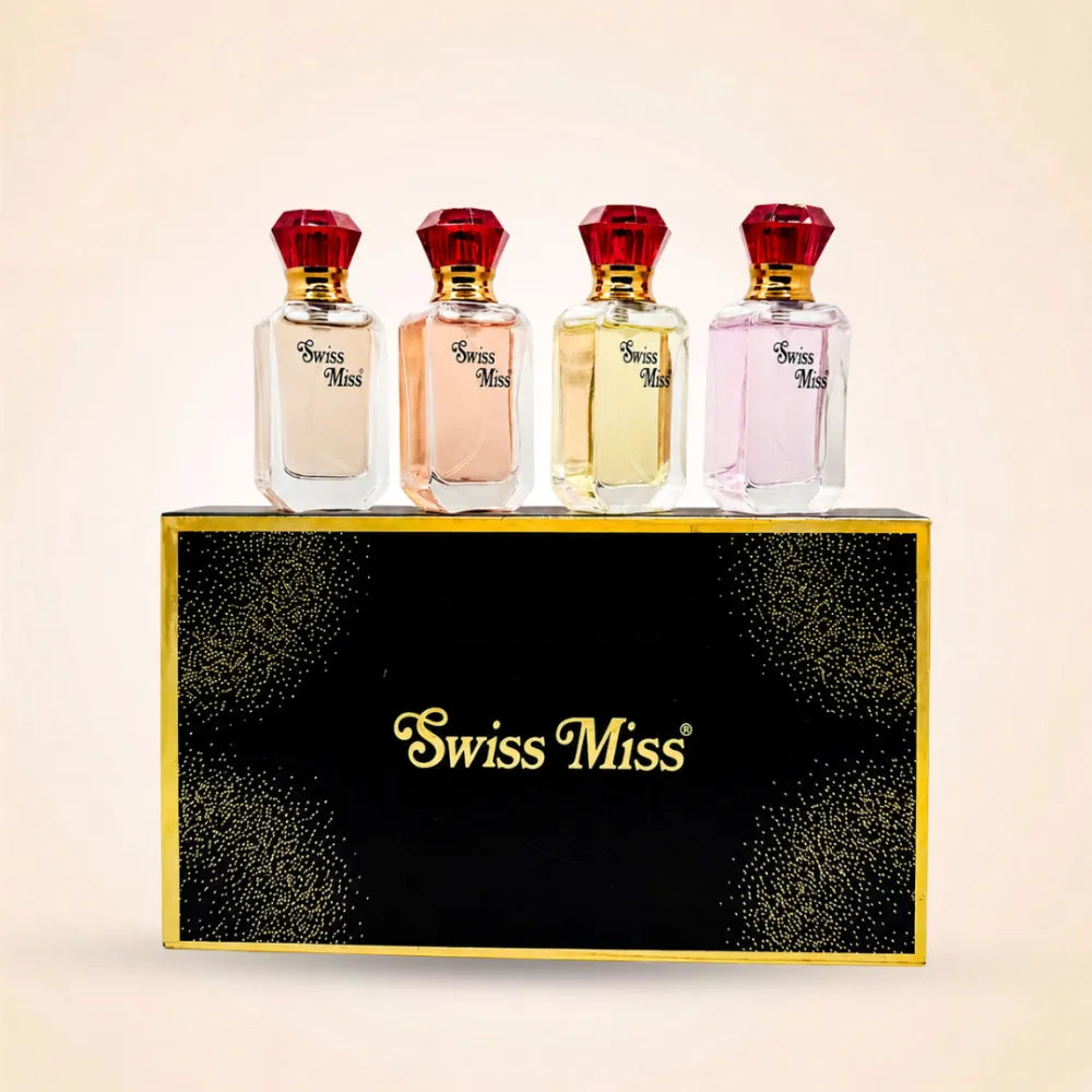 Four mini Swiss Miss perfume bottles with red jewel-style caps resting on a black and gold gift box.