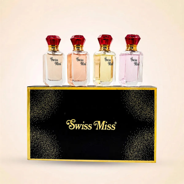 Four mini Swiss Miss perfume bottles with red jewel-style caps resting on a black and gold gift box.