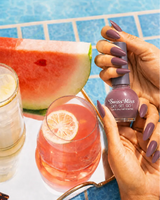 Hand holding Swiss Miss Maple Sugar 831 Get Set Go quick dry nail enamel bottle displaying sophisticated muted brownish-mauve polish applied on long nails.