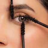 Extreme close-up of mascara wand bristles surrounding a model's eye to highlight the lash-separating and volumizing brush.