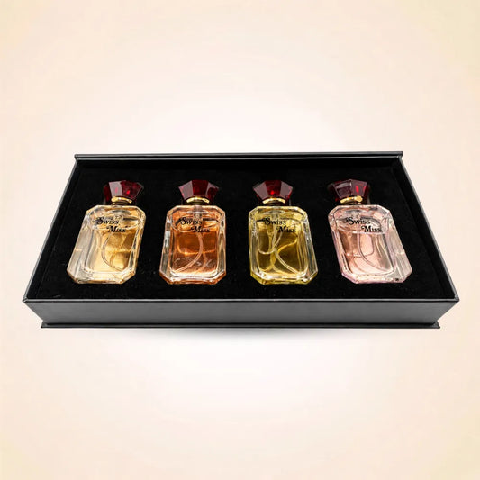 Top-down view of four Swiss Miss mini perfume bottles neatly set inside a black velvet gift box insert.