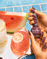 Woman holding Swiss Miss Get Set Go quick dry nail polish bottle in Moonless Nite 234 with a deep dusty mauve plum manicure by a pool.