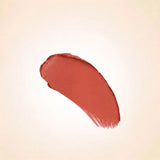 Warm peach nude texture swatch of Swiss Miss Nude Pink B-103 lipstick on a neutral background.