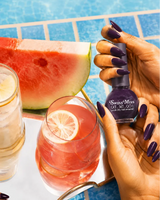 Hand holding Swiss Miss Plum Perfection F-402 Get Set Go quick dry nail enamel bottle displaying rich dark plum purple polish applied on long nails.
