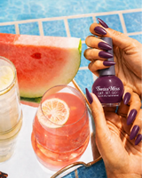 Hand holding Swiss Miss Purple Passion F-406 Get Set Go quick dry nail enamel bottle displaying rich deep royal purple polish applied on long nails.