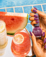 Hand holding Swiss Miss Raspberry Rose 257 Get Set Go quick dry nail enamel bottle displaying rich deep berry shade applied on long nails.