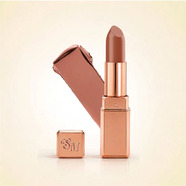 Swiss Miss Silk Lipstick in shade Caramel Nude (703) in gold bullet packaging shown alongside a textured cream color swatch.