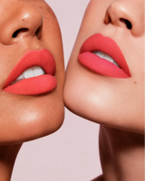 Close-up shot of two models with different skin tones wearing Swiss Miss Silk Lipstick in shade Coral Ice (727).
