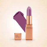 Swiss Miss Silk Lipstick in shade Lilac Mauve (723) in gold bullet packaging shown alongside a textured cream color swatch.