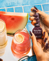 Hand holding Swiss Miss True Maroon 284 Get Set Go quick dry nail enamel bottle displaying rich dark maroon polish applied on long nails.