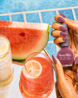 Hand holding Swiss Miss True Pink 271 Get Set Go quick dry nail enamel bottle displaying dusty mauvey pink polish applied on long nails.