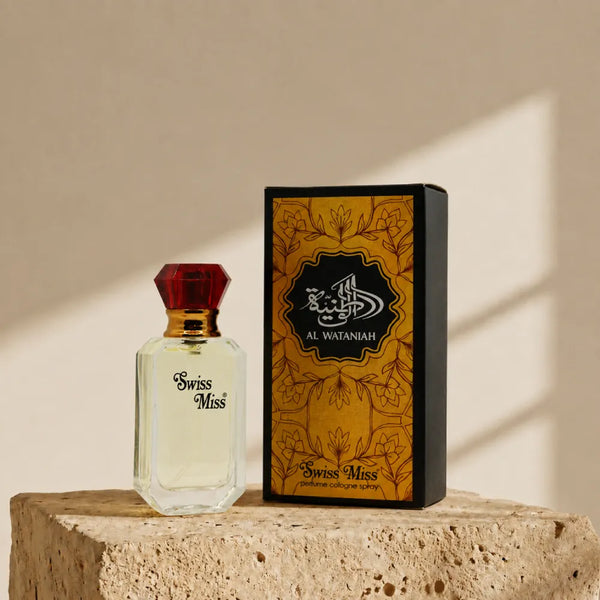 Swiss Miss Al Wataniah Perfume 15ml bottle with red diamond cap next to its gold patterned box on a stone pedestal