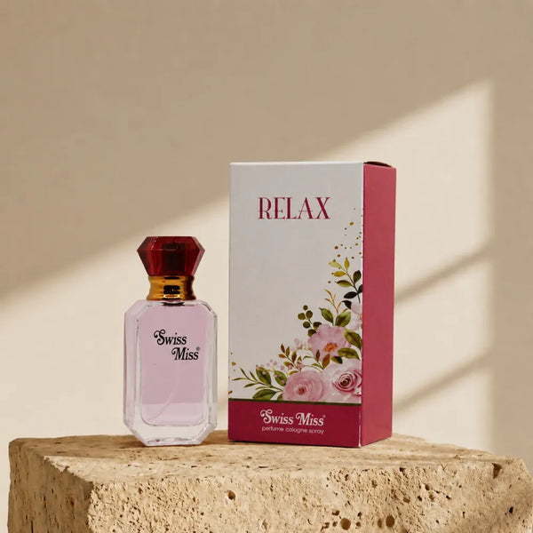Swiss Miss Relax Perfume 15ml bottle with red cap beside white floral packaging box on a stone pedestal